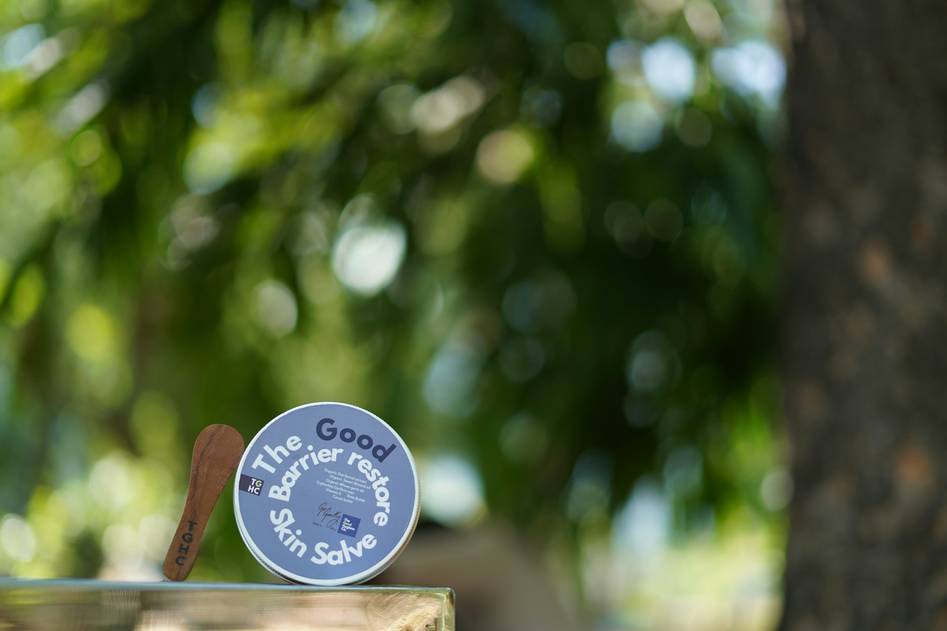 Close-up of hands applying a rich herbal body balm to dry skin