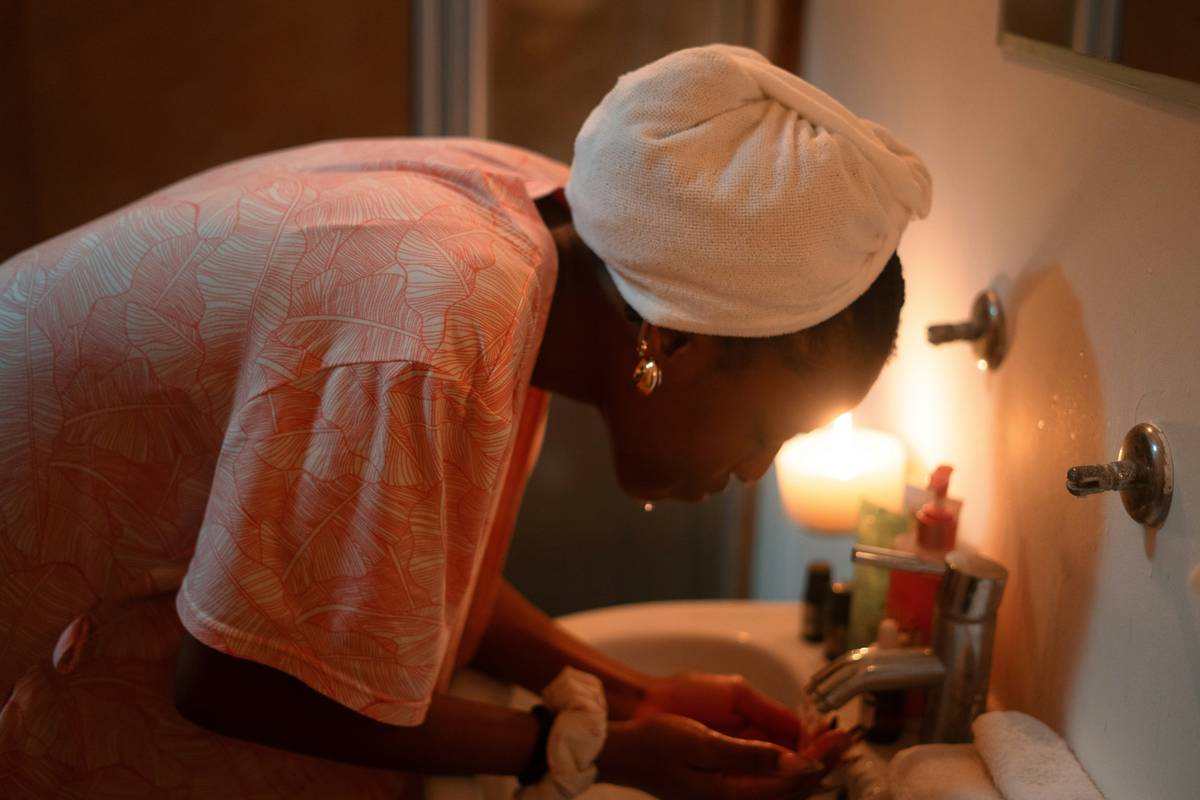 Woman applying cleansing balm for mature skin to dry face with fingertips, showing rich texture and gentle motion